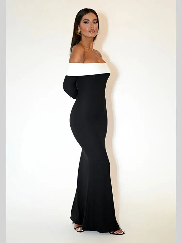 Side view of a woman in a black off-the-shoulder floor-length dress with a white trim.