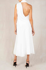 Back view of a woman in a white satin halter neck midi dress with an open back and a thigh-high slit.