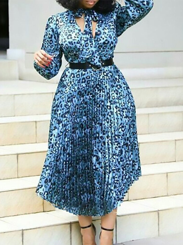 Woman wearing a blue leopard print midi dress with a bow neckline and pleated skirt, standing on stairs.