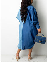 Back view of a woman wearing a two-tone blue oversized shirt dress with button-down front and adjustable drawstring hem, holding a studded handbag.