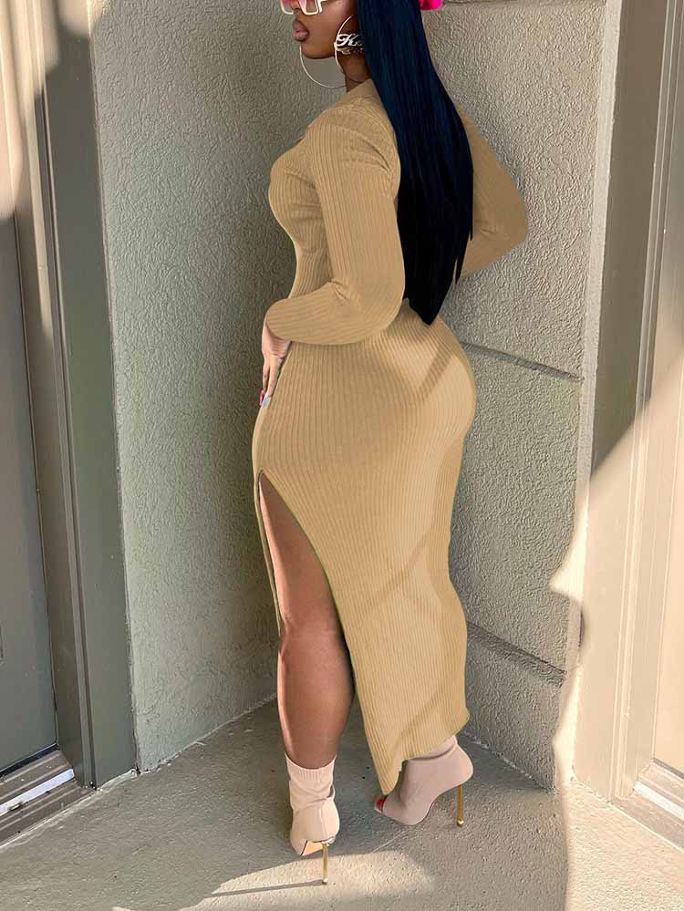 Back view of a woman wearing a tan ribbed knit midi dress with long sleeves and a high slit.