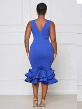 back view of a woman wearing a royal blue sleeveless v-neck dress with a ruffled mermaid hem