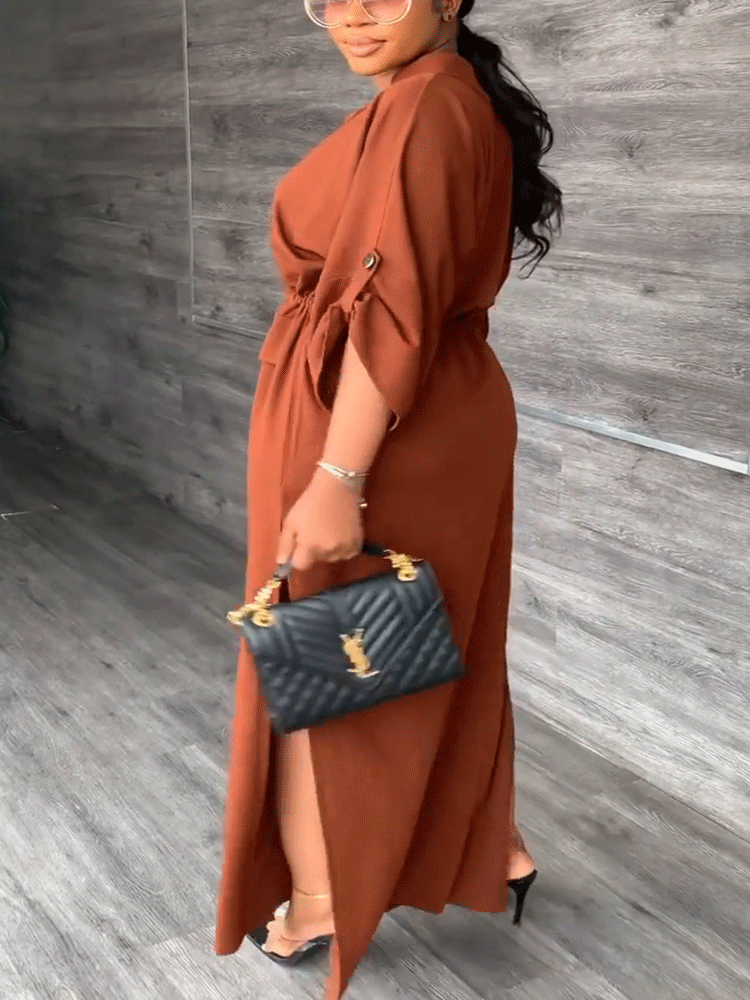 Woman in a rust-colored maxi dress with batwing sleeves, cinched waist, and side slits.