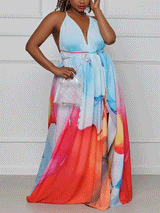 Front view of a woman holding a clutch and wearing a vibrant abstract print maxi dress with a V-neckline and tie waist.
