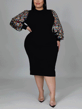 Side profile of a woman wearing a black sheath dress with sequined bishop sleeves and a mock neck.