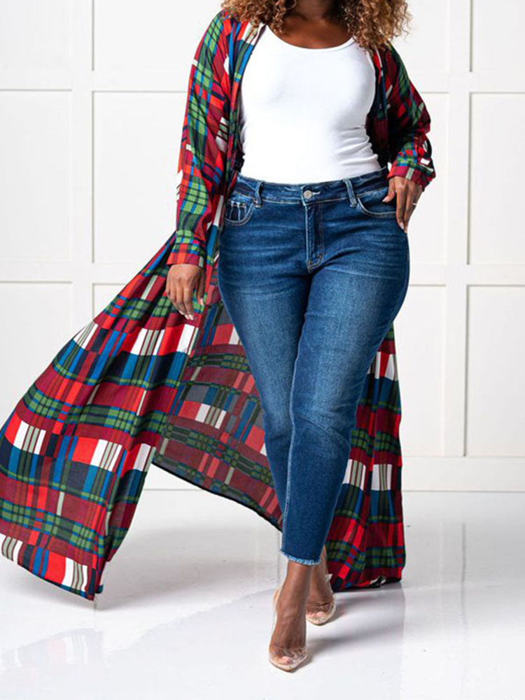 Woman wearing a long plaid duster over dark wash jeans and a white top, with the duster flowing
