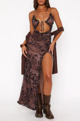 Woman wearing a brown tie-dye print sheer mesh maxi dress with a high slit and brown boots, posing against a white background with a brown cardigan draped over her shoulders.