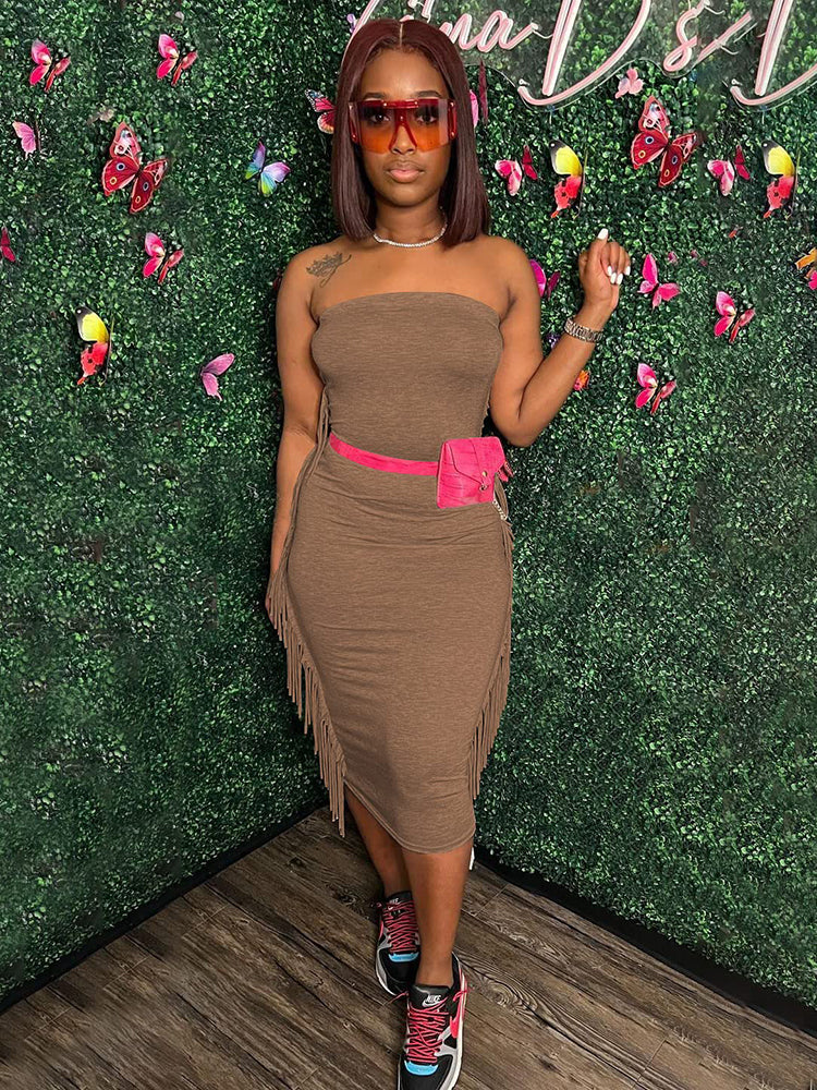 Woman wearing a brown strapless midi dress with fringe trim and a pink fanny pack, paired with sneakers.