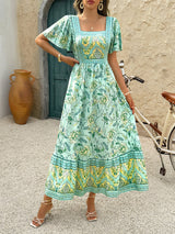 Woman wearing a light green floral print midi dress with a square neckline and short puff sleeves.