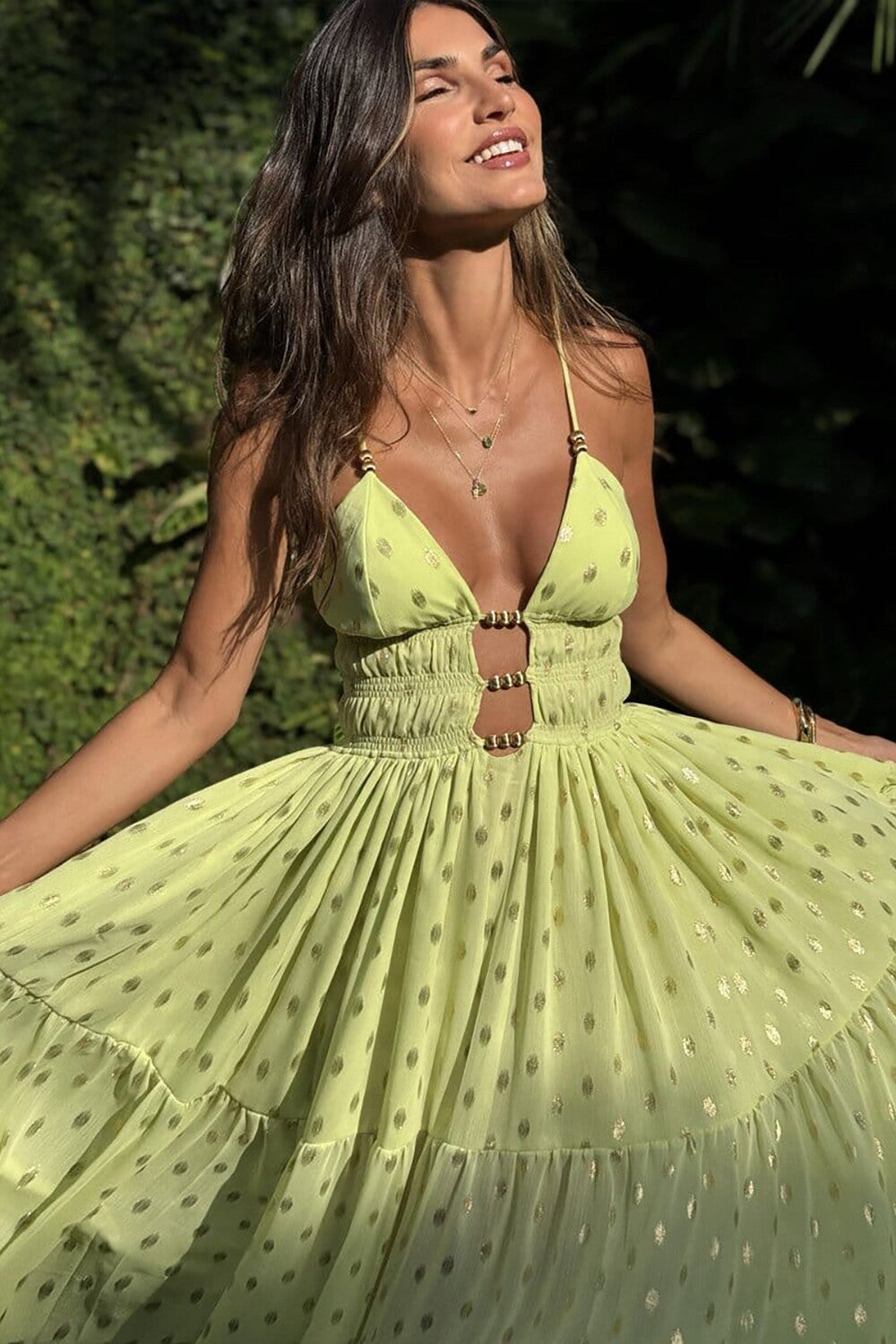 Close-up of a woman's torso in a lime green maxi dress with a plunging neckline and gold detailing.
