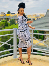Woman in a newspaper print t-shirt dress and black strappy heels, posing on a balcony with a glass of wine.