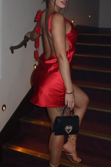 Close-up of a woman's back in a red satin slip dress with floral appliques.