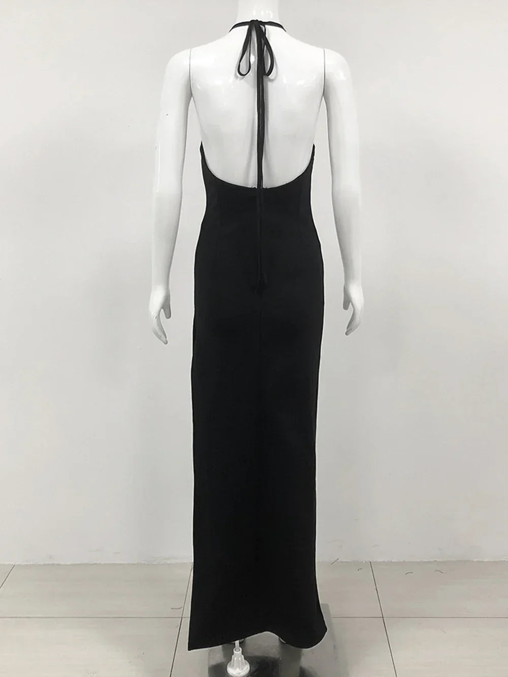 back view of a black floor-length halter dress with an open back and halter straps displayed on a mannequin
