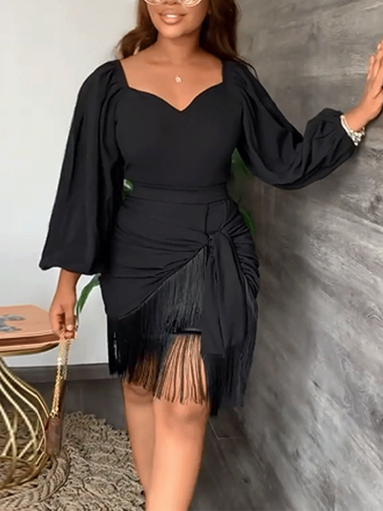 Woman wearing a black long puff sleeve dress with a sweetheart neckline, ruched detailing, tie detail, and fringe hem.