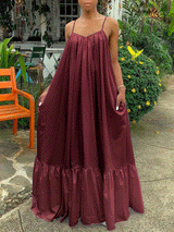 Woman wearing a flowing maroon maxi dress with ruffled hem and spaghetti straps, standing outdoors.