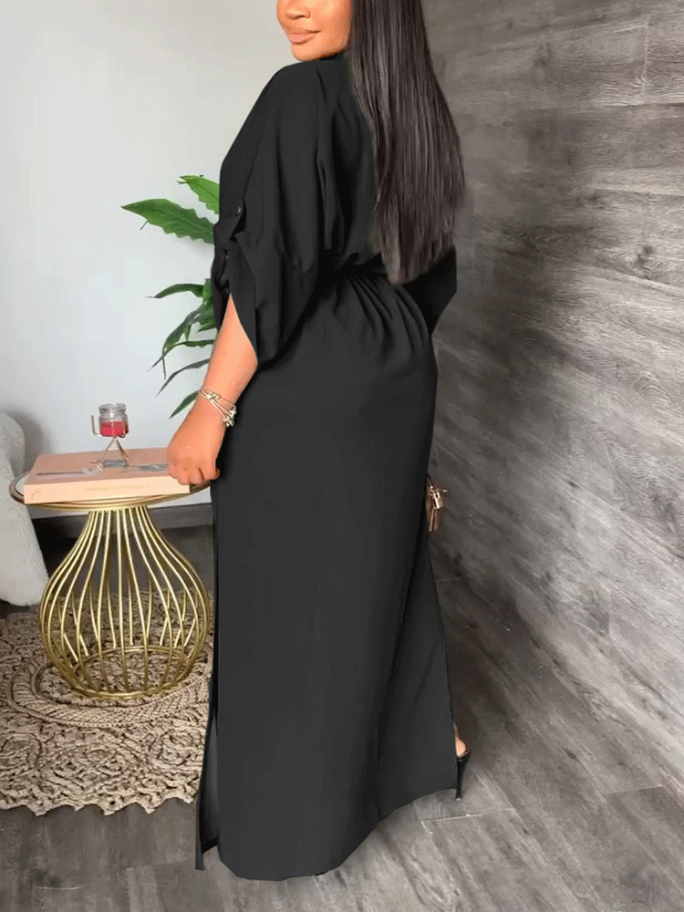 Back view of a woman in a long black dress with side slits.