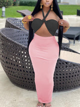 Woman wearing a black halter crop top with a knot detail and a light pink maxi skirt.