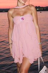 woman wearing a pink strapless babydoll dress with ruffled hem and floral embellishment