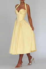 Side view of a woman in a pale yellow halter midi dress.