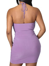 Woman wearing a lavender ruched halter dress, back view.