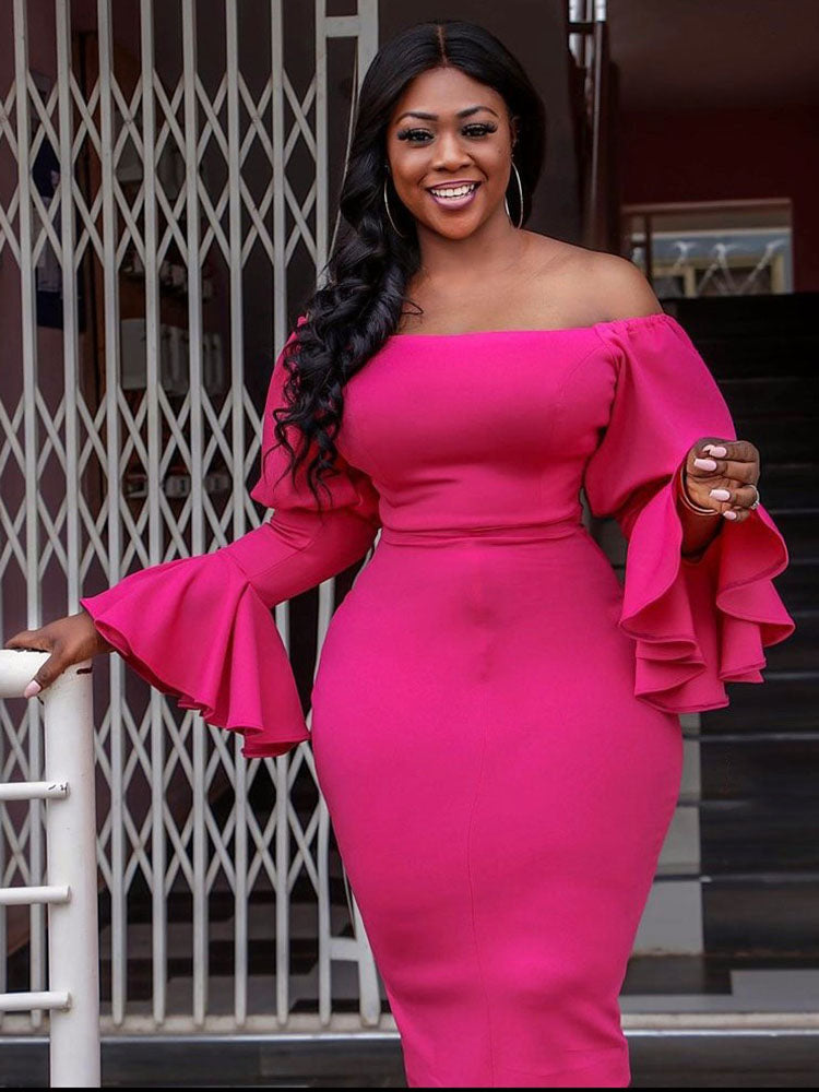 Woman in a bright pink off-the-shoulder dress with ruffled sleeves, leaning on a railing.