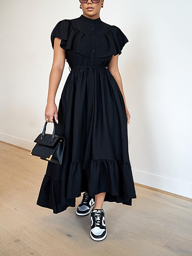 Woman wearing a black ruffled midi dress with sneakers and a handbag.