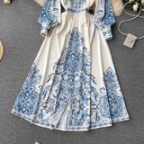 A full shot of the white maxi dress with blue paisley print, showcasing the skirt and its slit detail.