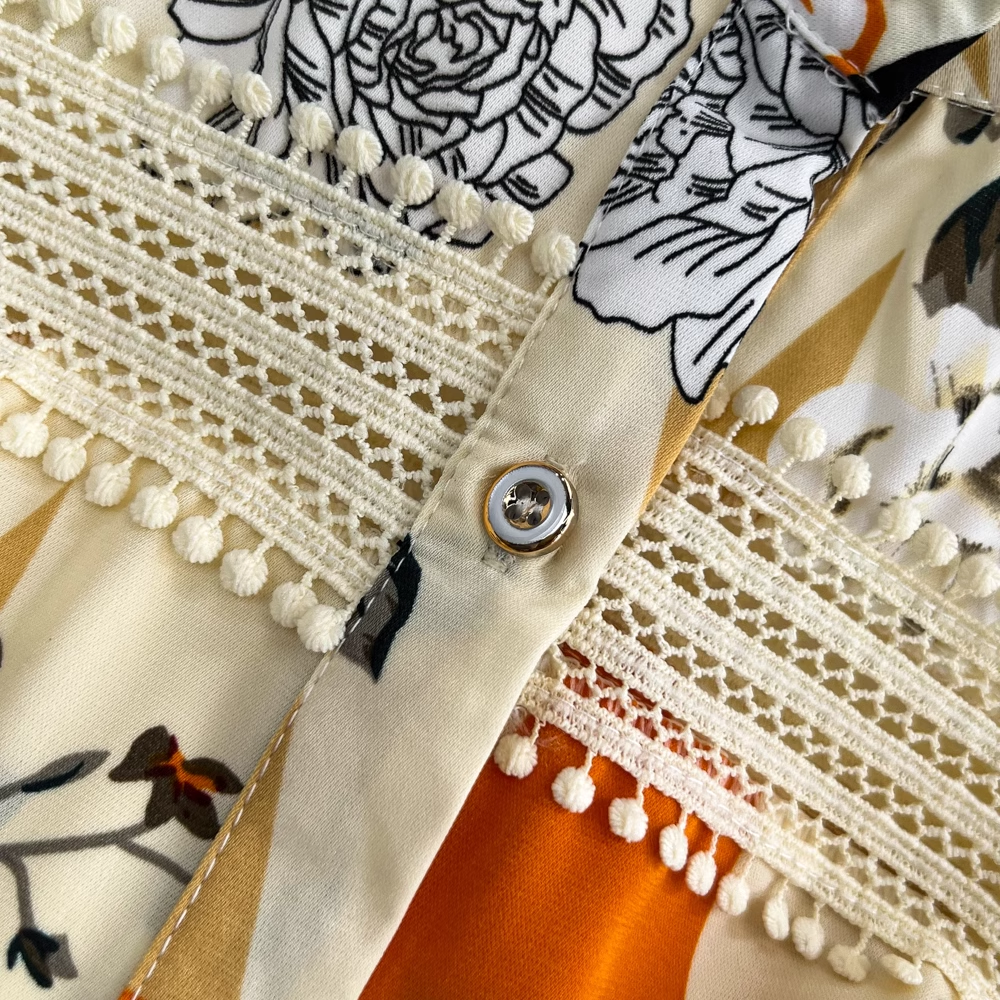 Detail of the button and lace trim on a floral and geometric print maxi dress.