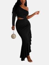 Woman wearing a black one-shoulder, long-sleeved maxi dress with a cut-out waist and ruffled asymmetrical hem, holding a round metallic clutch.