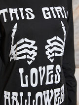 Close-up of the 'THIS GIRL LOVES HALLOWEEN' graphic on a black long-sleeved dress.