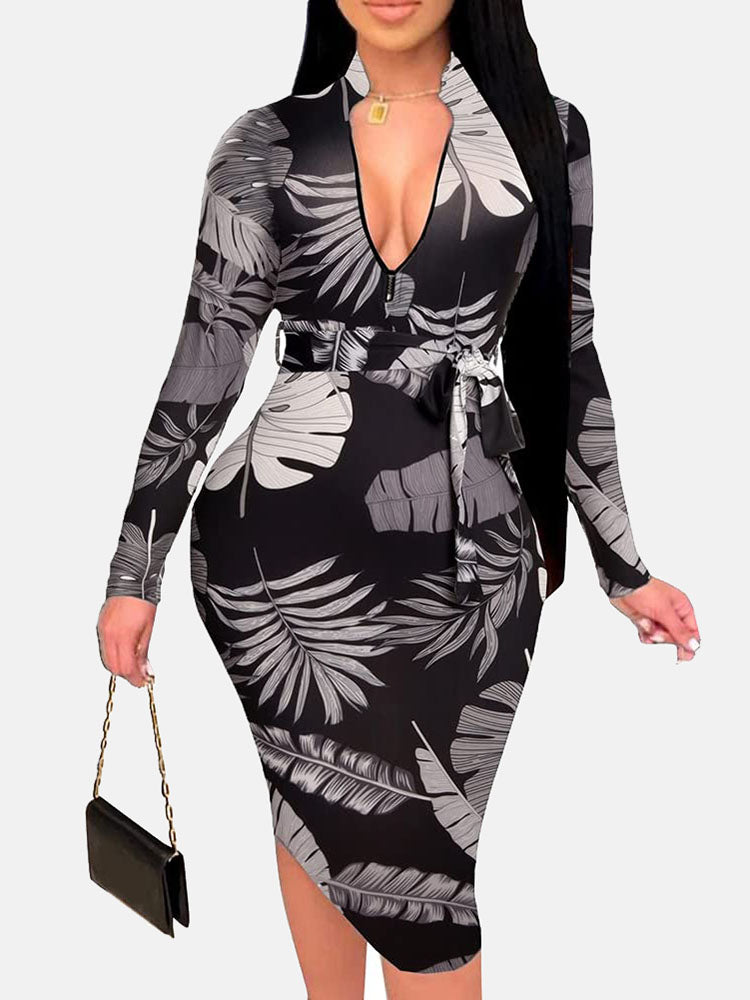 Woman in a black midi dress with a grey and white leaf print, V-neck, long sleeves, and a belted waist.