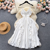 White satin cami dress with ruffled skirt laid flat, featuring a straw hat and floral accents.