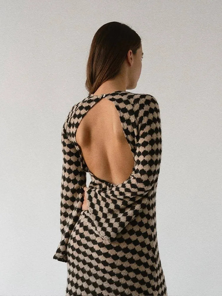 Back view of a woman wearing a long-sleeved knit dress with an open back and a black and beige geometric diamond pattern.