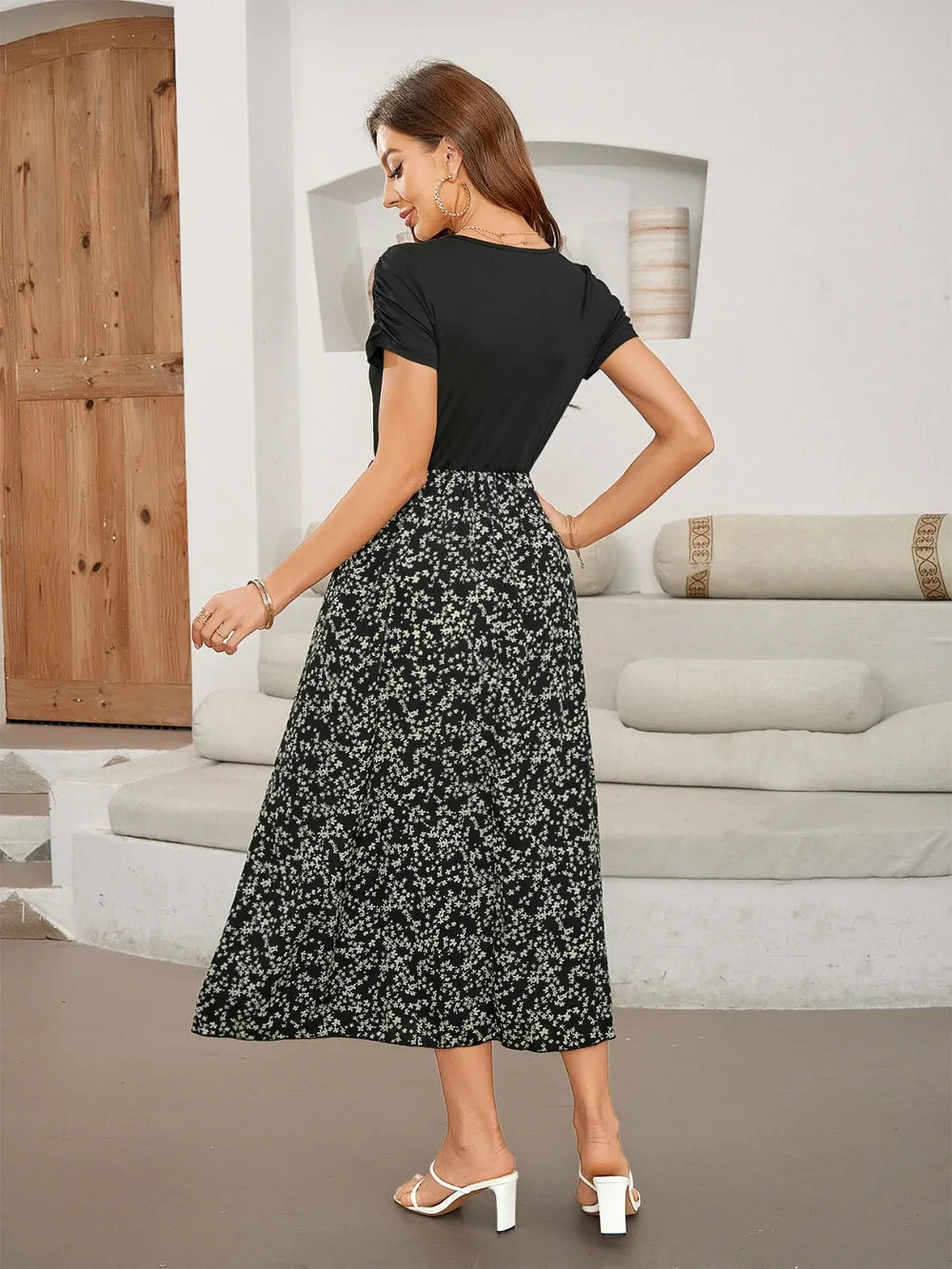 Rear view of a woman in a black short-sleeve top and a floral print midi skirt.