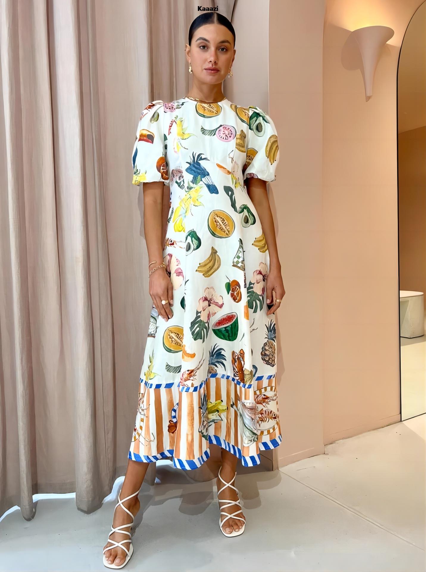 Full-body shot of a woman in a white midi dress with a vibrant tropical print, featuring puff sleeves and a detailed hem, posing indoors.