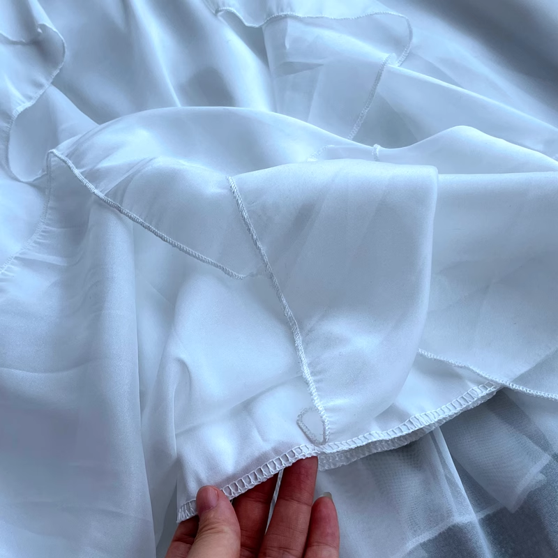 Detail of the ruffled hem of a white chiffon dress
