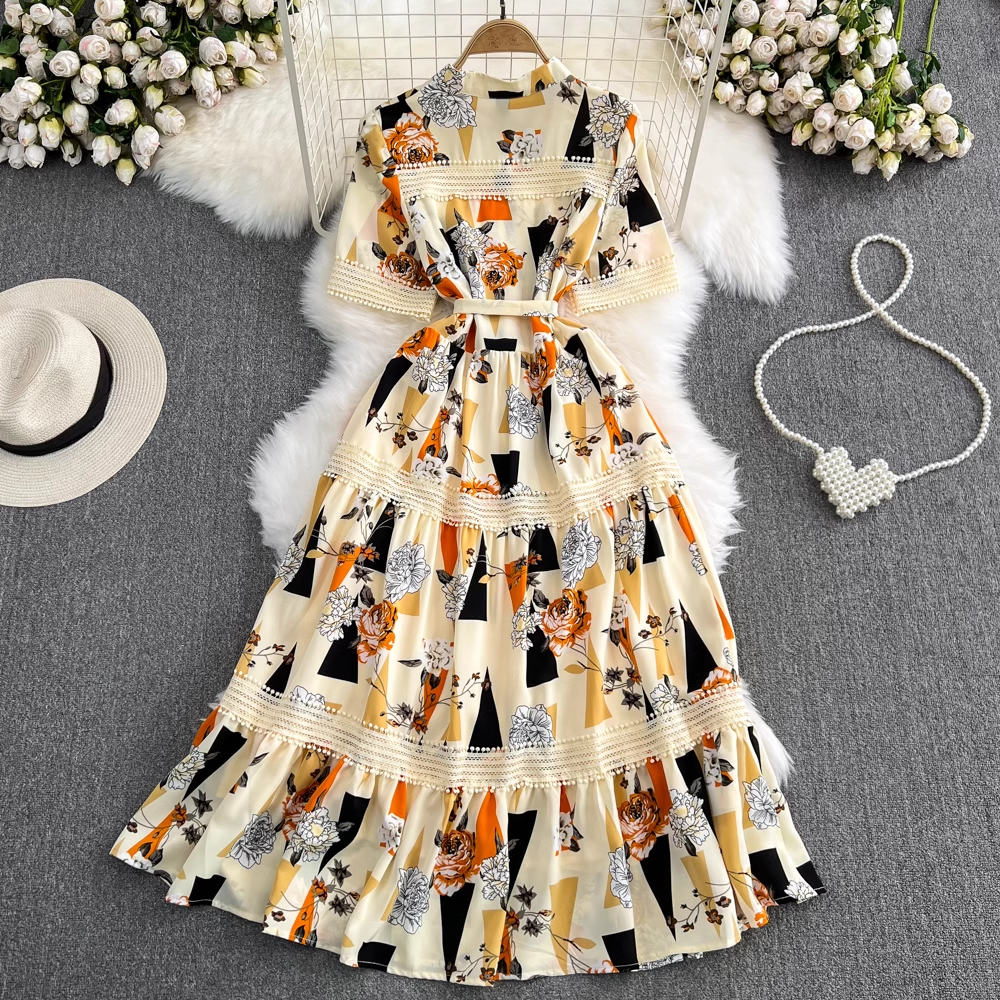 A floral and geometric print maxi dress laid flat on a faux fur rug, showing the tiered skirt.