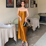 woman wearing a gold pleated slip dress and black strappy sandals