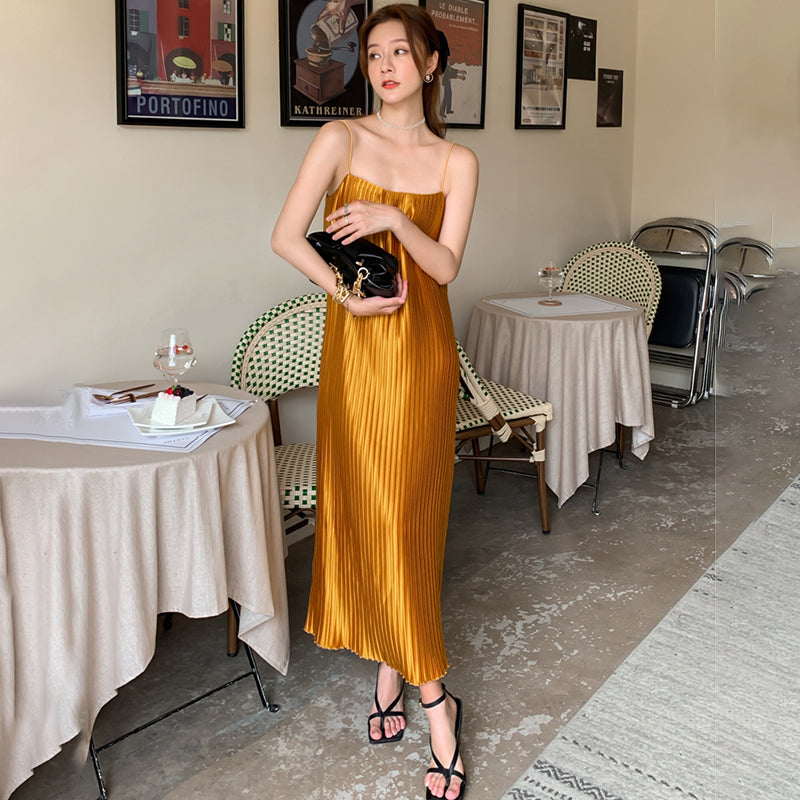 woman wearing a gold pleated slip dress and black strappy sandals