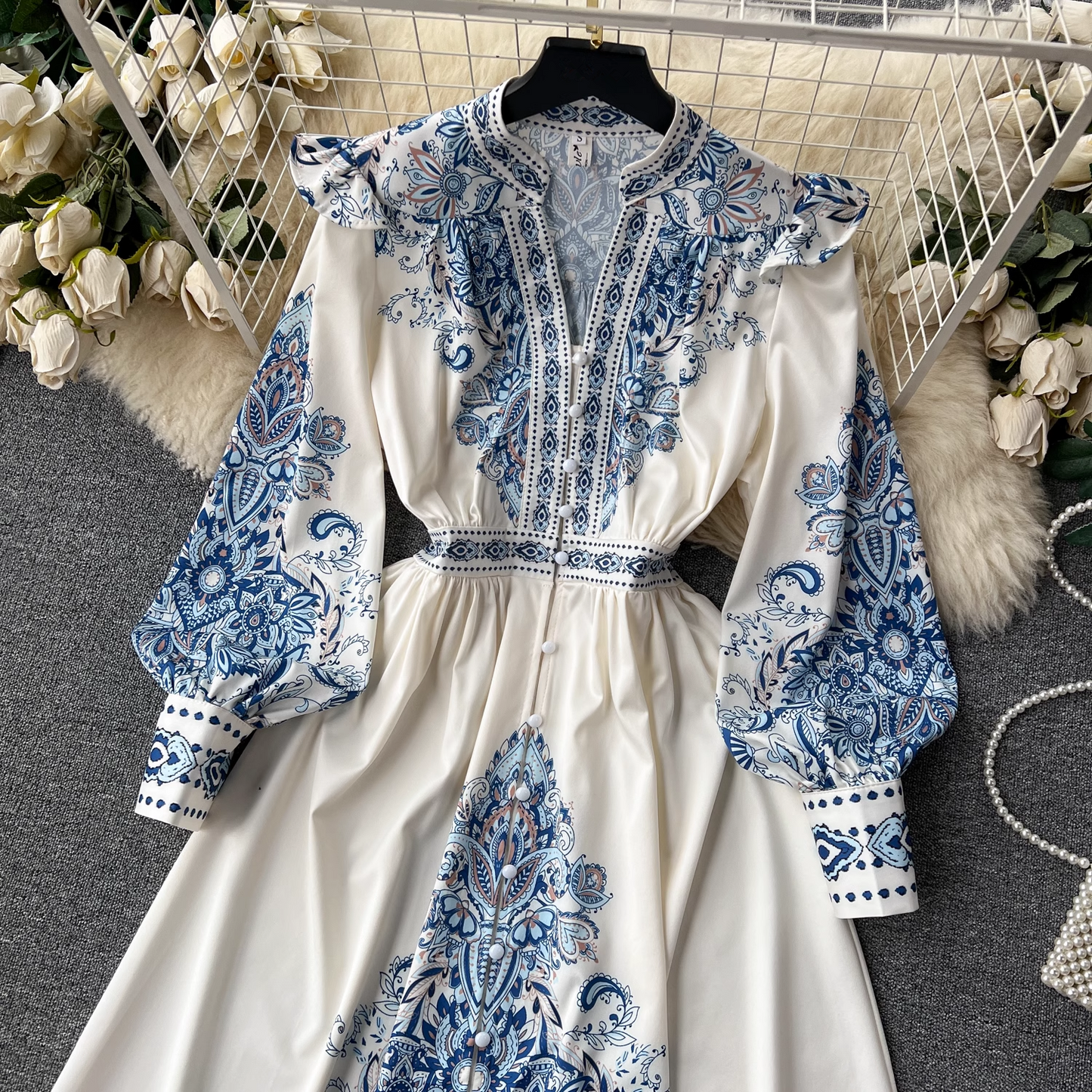 Close-up view of the top portion of the white maxi dress with blue paisley print, highlighting the neckline and sleeves.