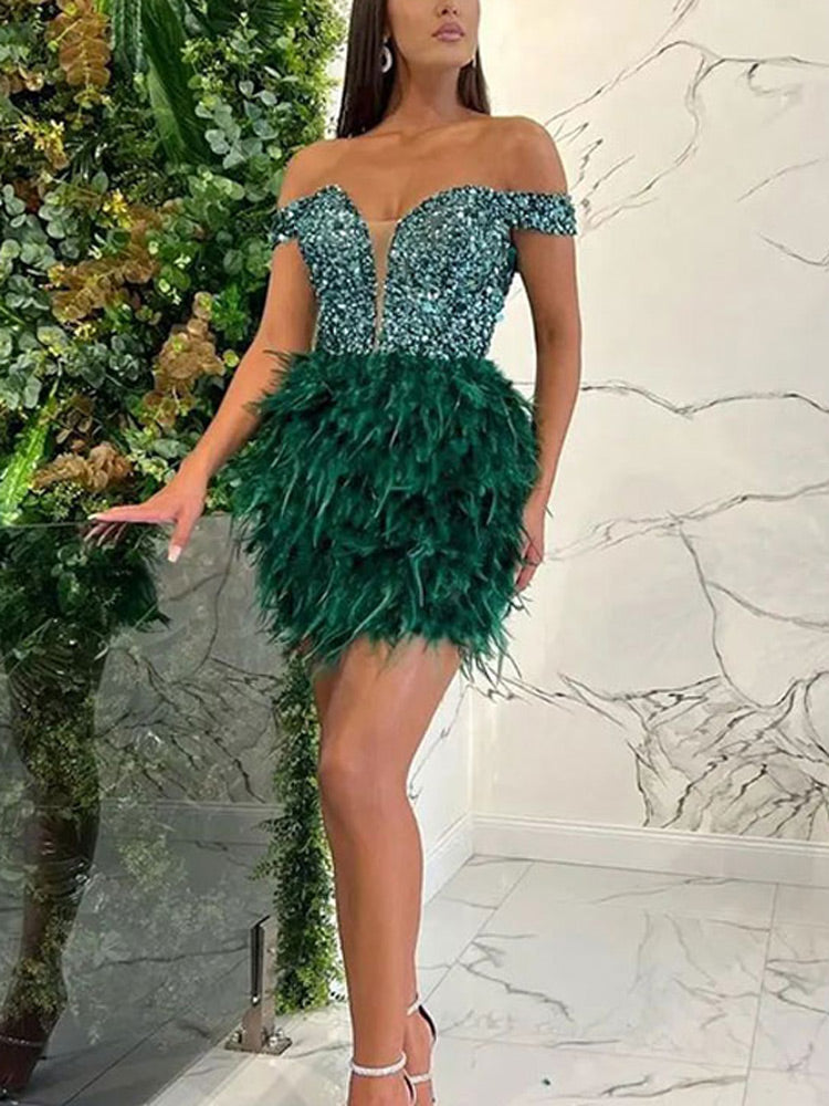 Woman wearing a forest green off-the-shoulder mini dress with a sequined bodice and a feather skirt.