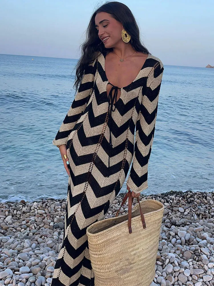 Woman wearing a black and beige chevron knit maxi dress on a pebble beach