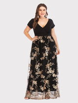 Front view of a plus-size model in a black and gold sequined maxi dress, posing with one hand on her hip