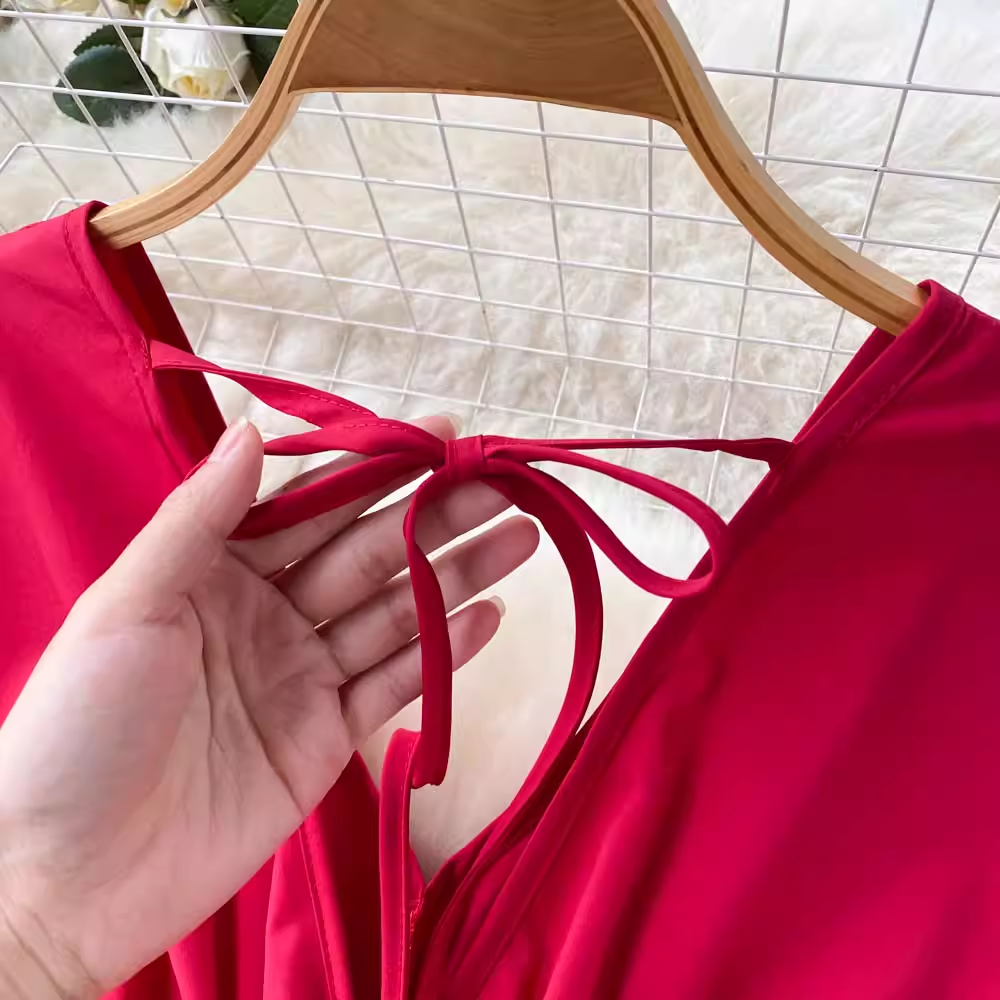 Hand tying a bow at the back of the red maxi dress