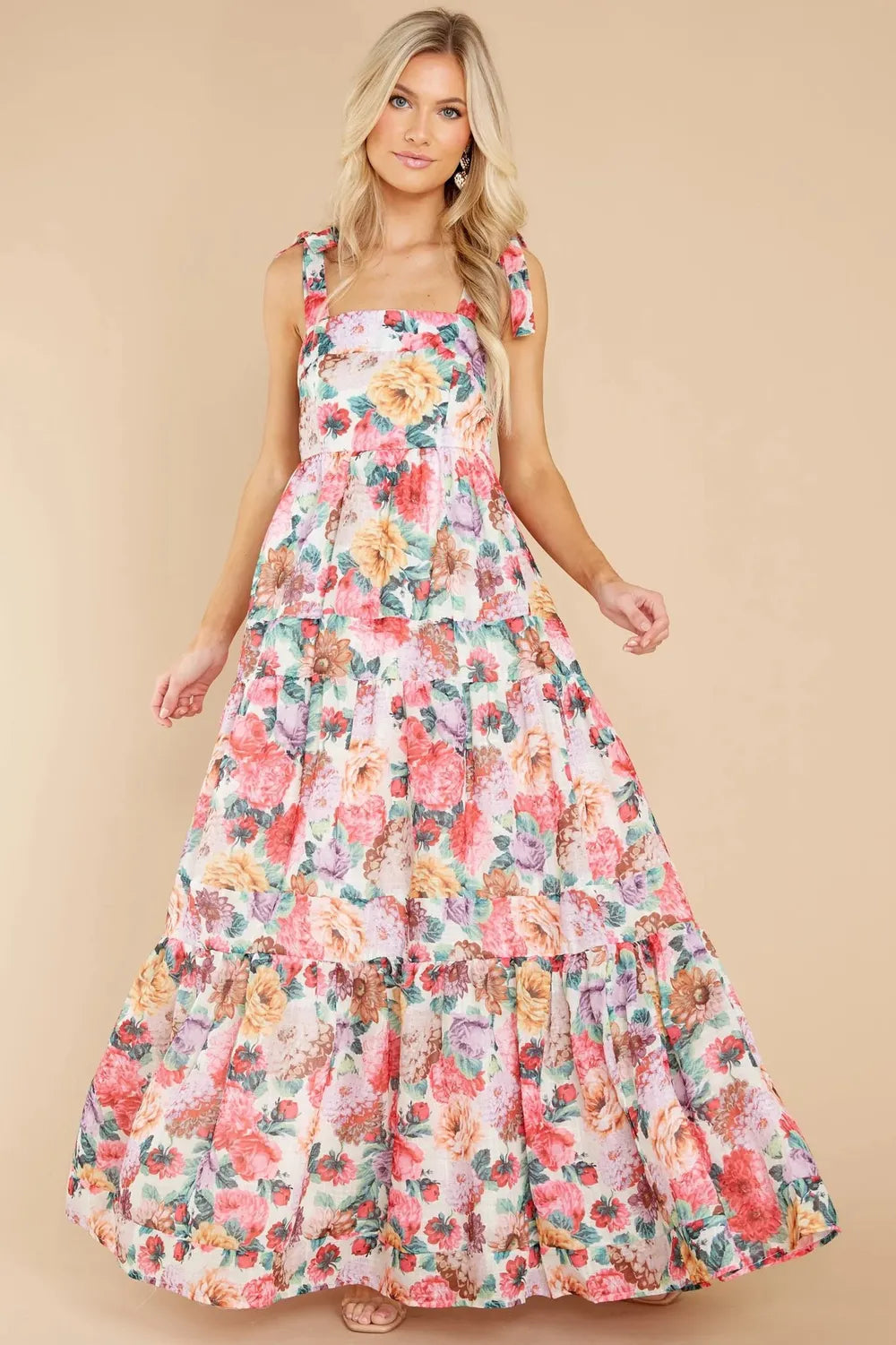 Full-body shot of a woman in a tiered floral maxi dress with tie shoulders.