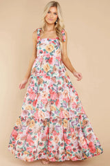 Full-body shot of a woman in a tiered floral maxi dress with tie shoulders.