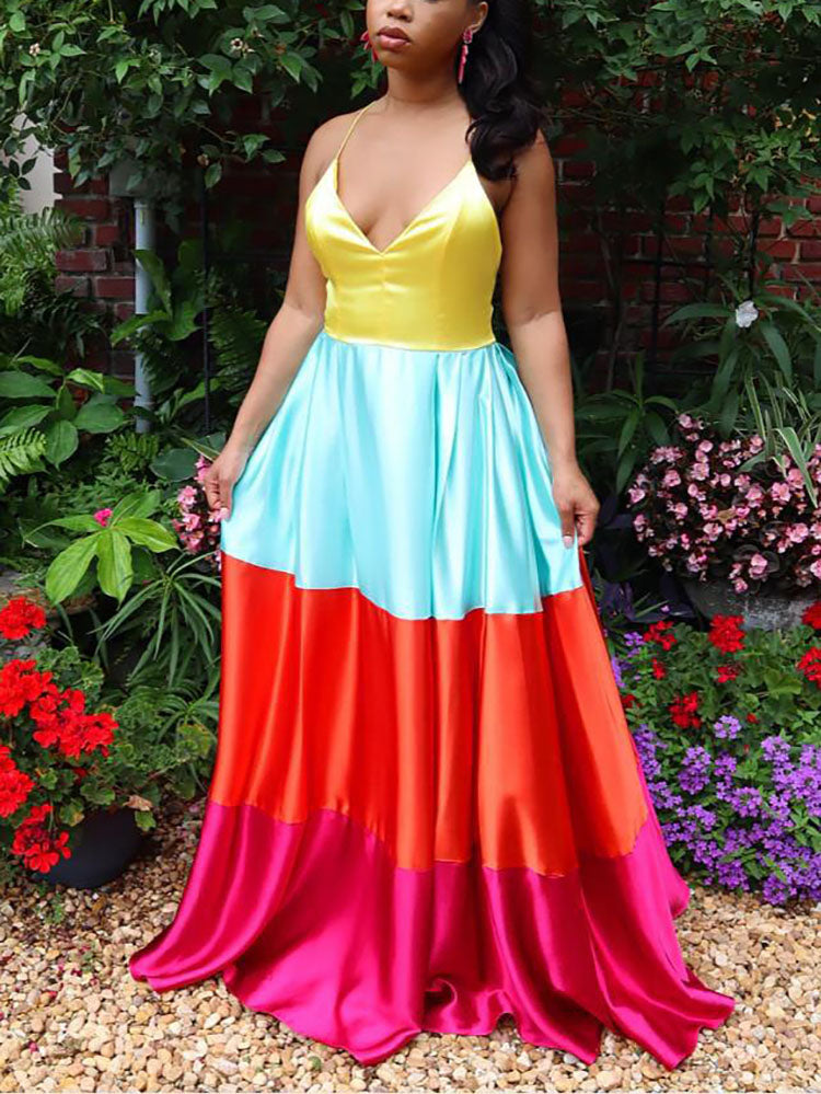 Woman wearing a yellow, light blue, orange, and pink colorblock satin maxi dress, standing outdoors.