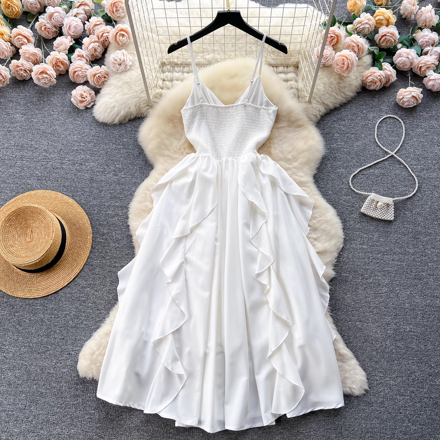 Back view of a white satin cami dress with ruffled skirt laid flat, showcasing smocked back detail.