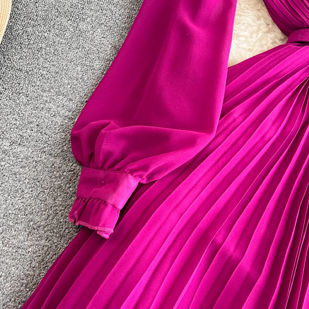 Close-up of the puff sleeve and cuff of a magenta pleated midi dress.
