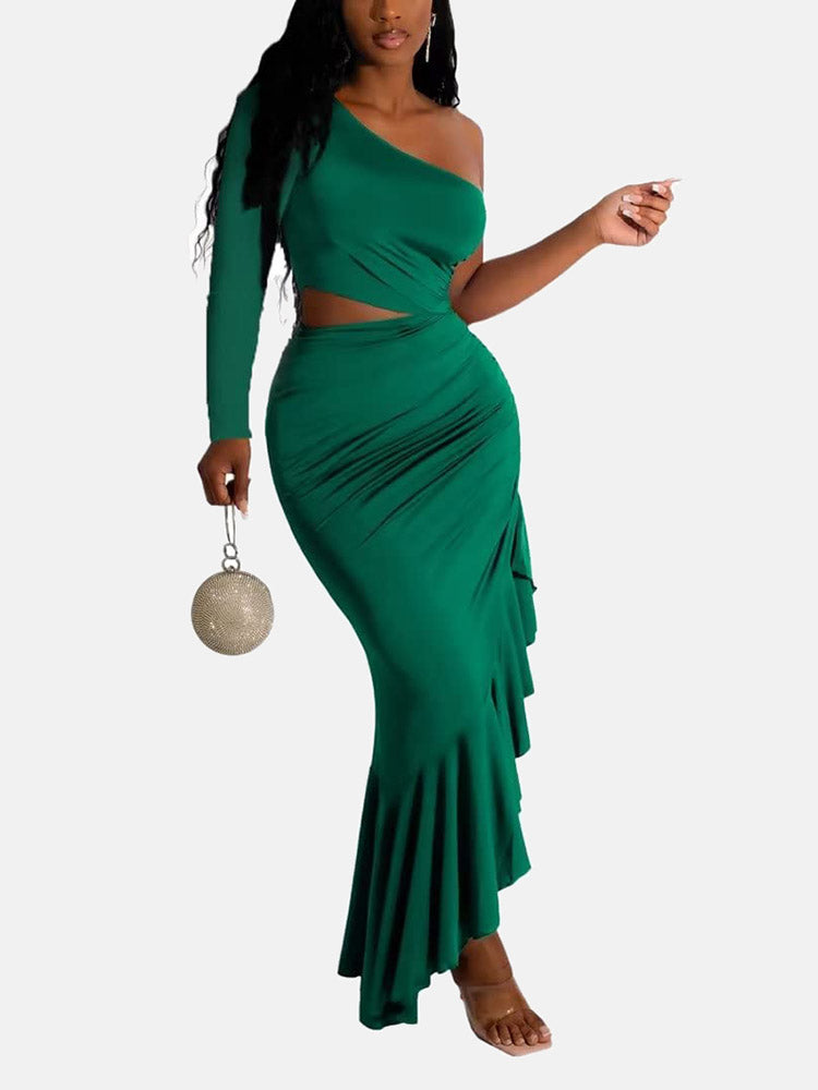 Woman wearing a green one-shoulder, long-sleeved maxi dress with a cut-out waist and ruffled asymmetrical hem, holding a round metallic clutch.